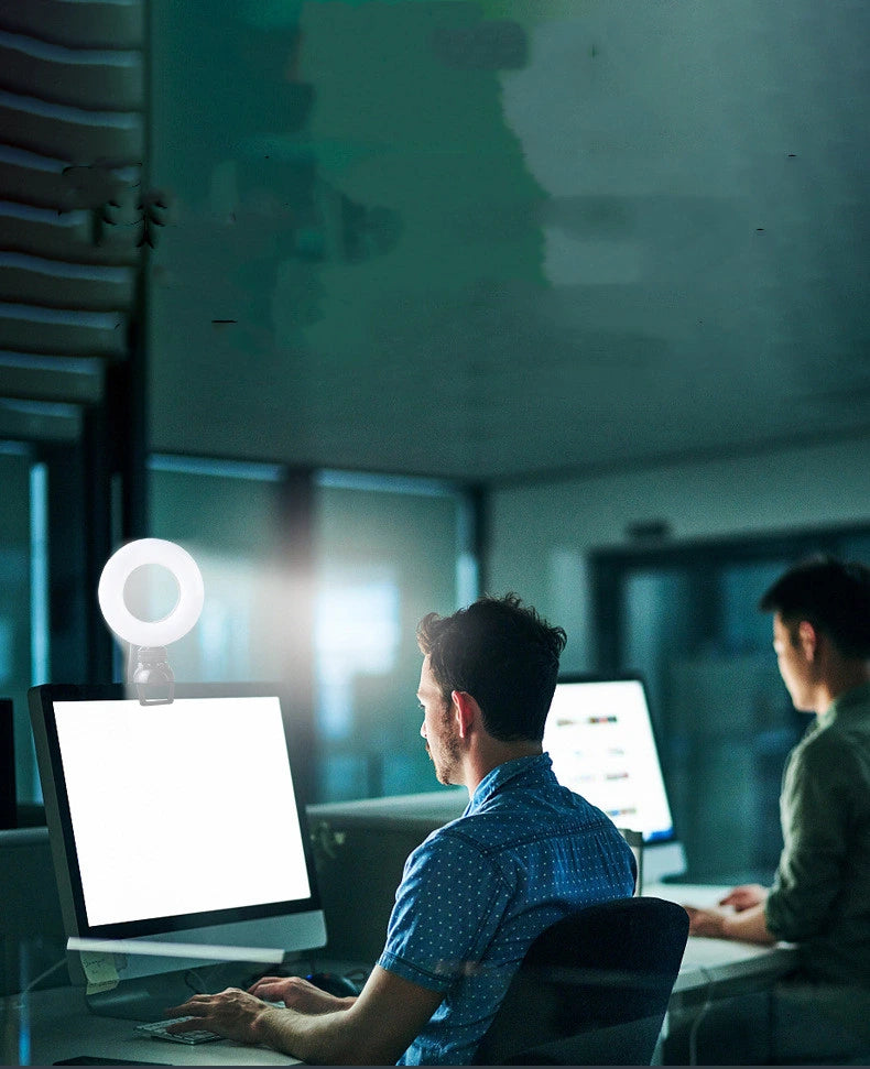 Two people working on computers in a dimly lit office setting.