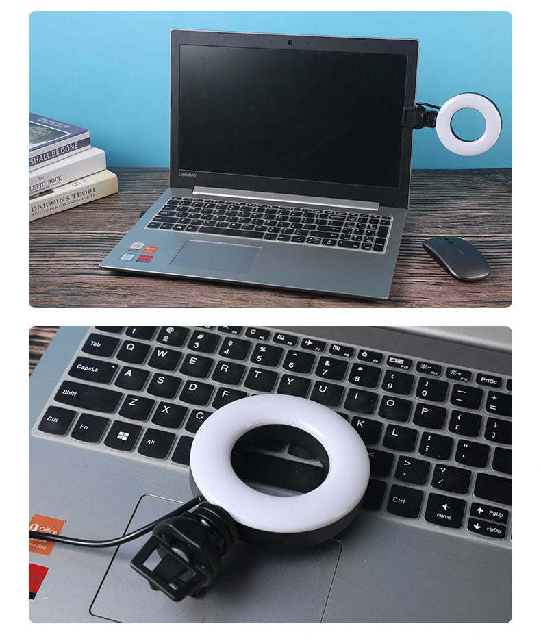 Laptop with a ring light attached on a desk with books and a phone.