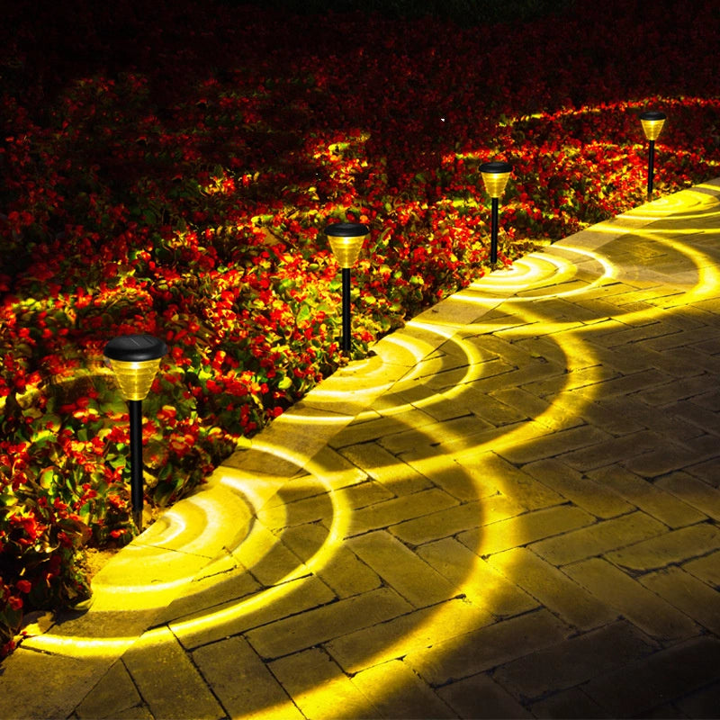 Glowing solar lights on a garden path with flowers in the background