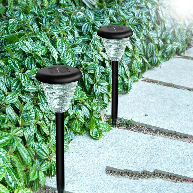 Two solar-powered outdoor lights on a pathway with greenery in the background